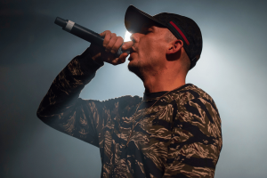 Capital Bra performing live on stage with microphone during concert amid Germany gambling regulator fine controversy. Germany regulator targets Capital Bra over alleged illegal gambling promotion case