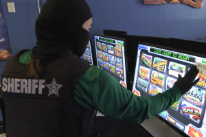 Florida sheriff investigator examines illegal gambling slot machines during Manatee County arcade enforcement raid and statewide Florida gaming crackdown