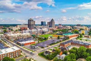 Aerial view of downtown Greensboro, North Carolina, featuring the city skyline, baseball stadium, commercial buildings, and surrounding neighborhoods. New Lumbee website explains upcoming tribal gaming amendment vote before June