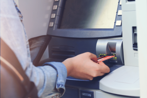 Person inserting bank card into ATM during cash withdrawal transaction at Citizens Bank style automated teller machine. Pennsylvania bank manager imprisoned after stealing funds to support gambling habit