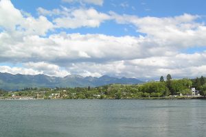 An image of Polson, Montana with a lake in the foreground and mountains in the background.