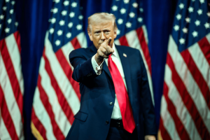 Donald Trump points during campaign-style appearance surrounded by American flags amid debate over prediction markets and CFTC regulation.