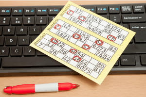 Online bingo card beside computer keyboard as UK Gambling Commission announces stricter gambling industry regulations and compliance rules