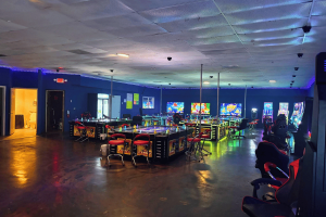 Interior of 999 Arcade illegal gambling venue in Charlotte, North Carolina, showing rows of gaming machines, gambling stations, neon lighting, and seating areas during a CMPD investigation into alleged illegal gambling operations.