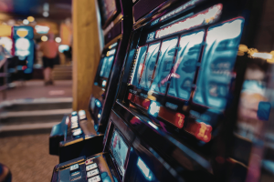 A row of illuminated slot machines in a casino-style setting, used to illustrate Michigan authorities seizing illegal gambling devices during an Adrian enforcement operation.