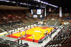 Interior view of a college basketball arena during a game warmup, featuring a hardwood court, scoreboard, spectator seating, and fans inside the Fresno State Save Mart Center in California. Nevada betting probe leads to arrest in Fresno State basketball case