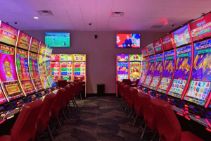 Interior view of Two Coppers Casino in Juneau, Alaska, featuring rows of electronic gaming machines, red chairs, bright slot displays, and overhead television screens during the casino’s soft opening.