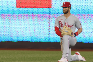 Bryce Harper of the Philadelphia Phillies kneels on the field before an MLB game amid FanDuel Cameo gambling promotion controversy.