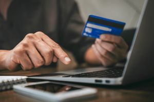 Person using a credit card to make an online payment on a laptop, illustrating digital payment processing and online gambling transactions. EGBA complaint targets Walletto over alleged illegal gambling payments in Lithuania