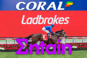 Entain begins restructuring with 500 job cuts as tax pressures mount. Coral and Ladbrokes branding displayed on a racetrack billboard as a jockey rides a racehorse past, with a large Entain logo overlaid in the foreground.