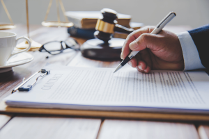 Close-up of an attorney signing a legal contract as NCLGS challenges the CFTC's proposed sports prediction markets rule over sports betting regulation and state authority.