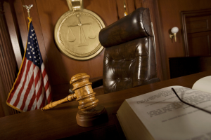 Judge's gavel on courtroom bench with American flag and justice scales symbol in courthouse during criminal court proceedings. Roosevelt enforcement operation leads to two arrests as illegal gambling machines seized