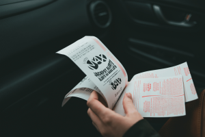Person holding lottery tickets inside a car as US gambling participation declines. Fewer Americans gambling as lotteries and casinos lose participants, survey says
