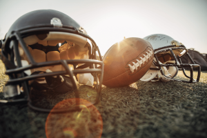 American football helmets and football on field representing NFL sports betting partnerships